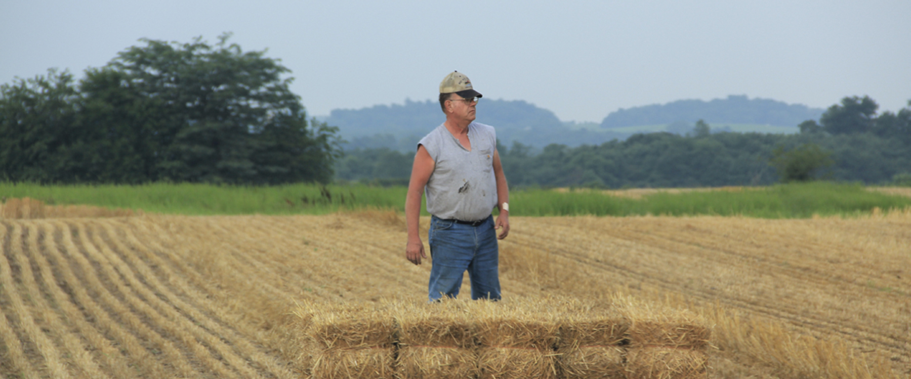 man standing in straw field